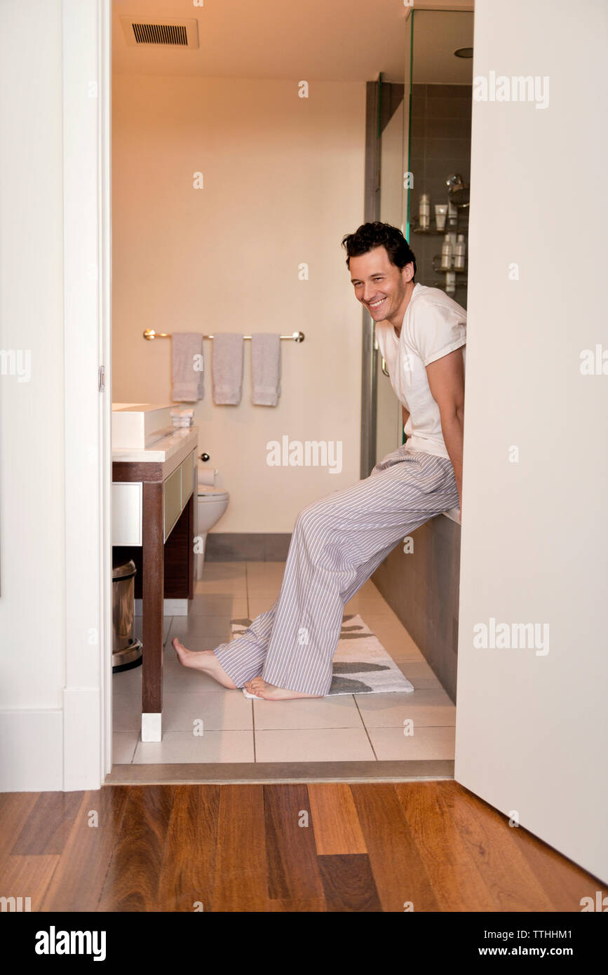 Cheerful man sitting on bathtub in bathroom Stock Photo Alamy