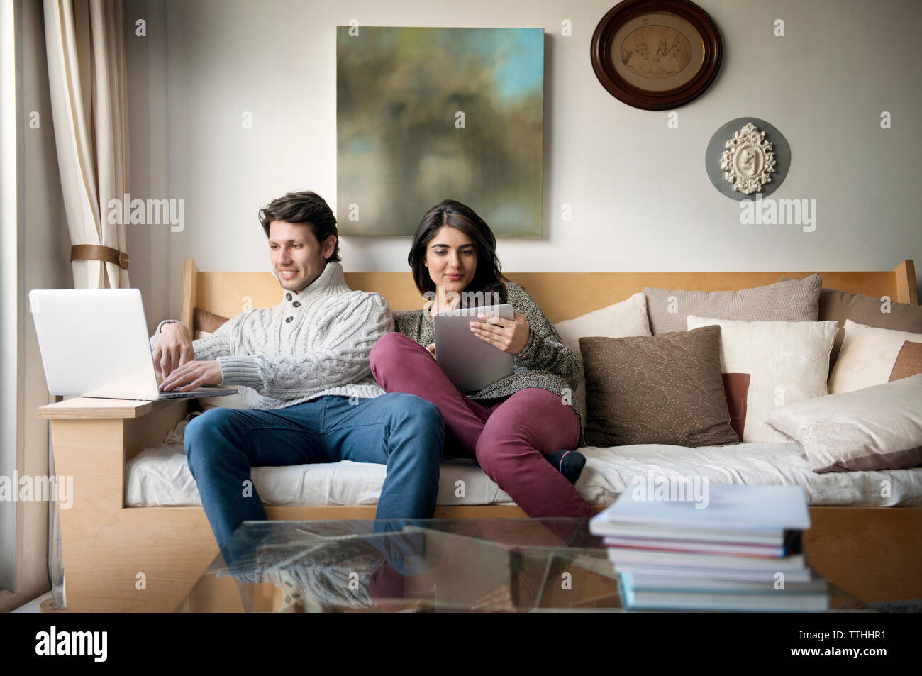 Young couple using technologies on sofa at home Stock Photo