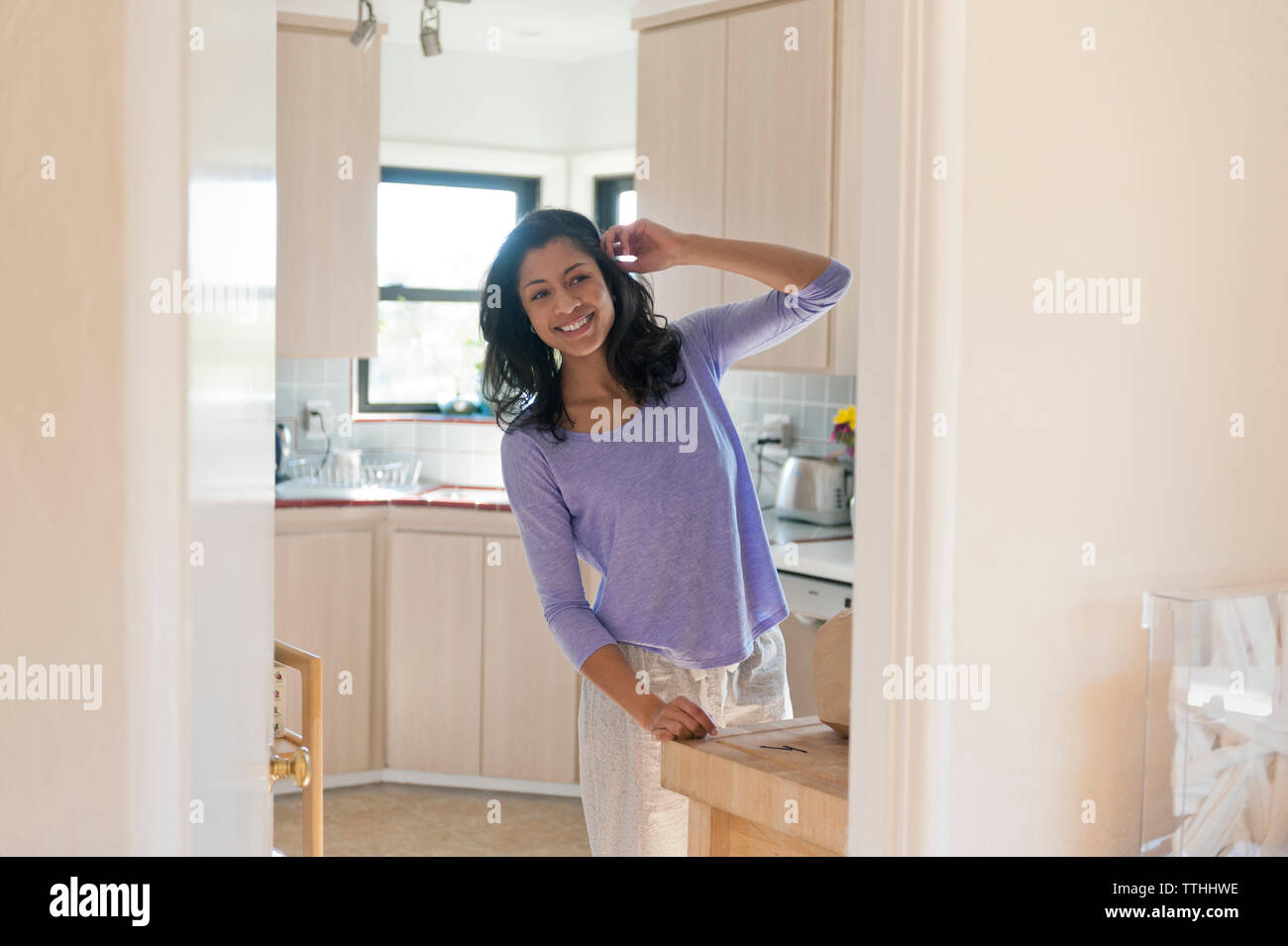 Cheerful woman standing in domestic kitchen Stock Photo