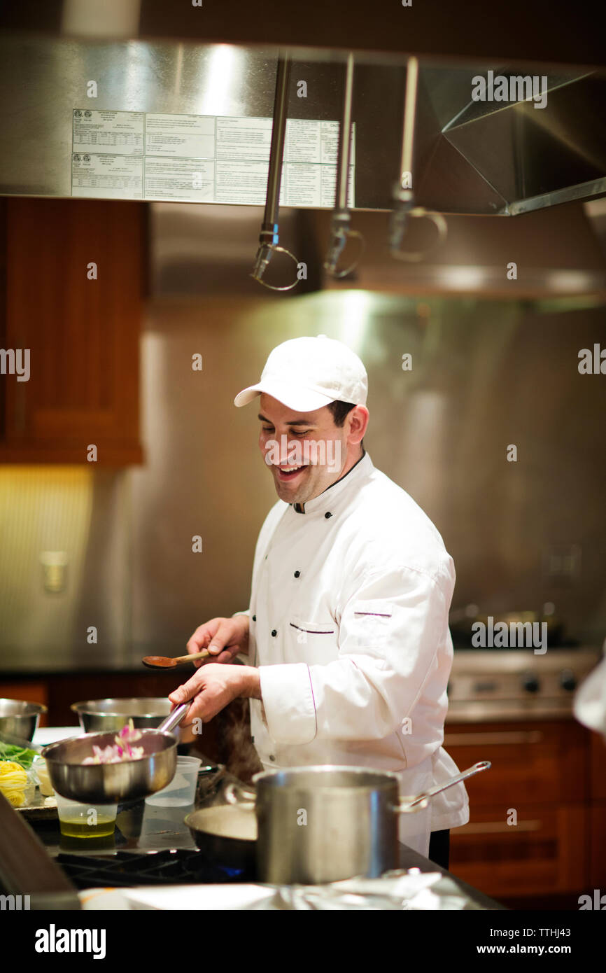 Happy chef cooking while standing at commercial kitchen Stock Photo