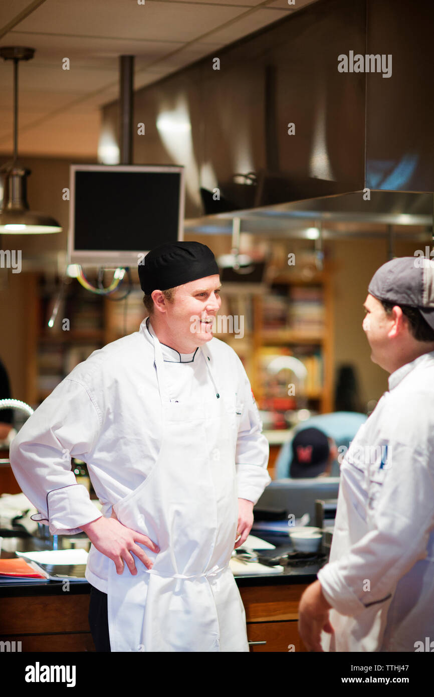 Male chefs talking while standing in commercial kitchen Stock Photo