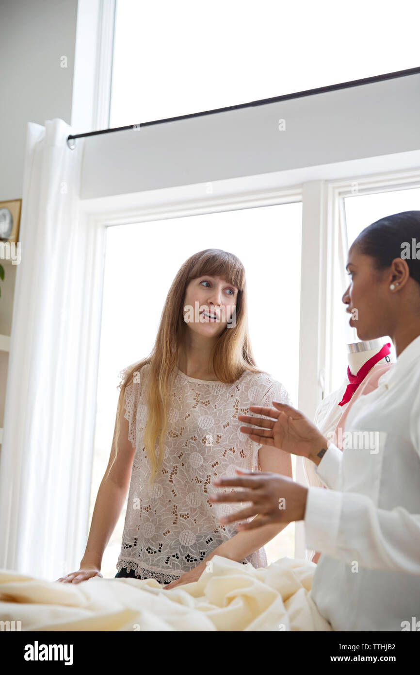 Female designers having discussion over fabric in studio Stock Photo