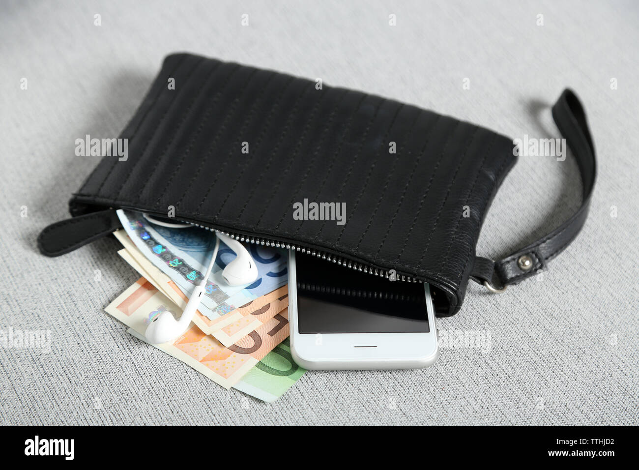 Leather purse with mobile phone and euro banknotes on grey cloth background Stock Photo