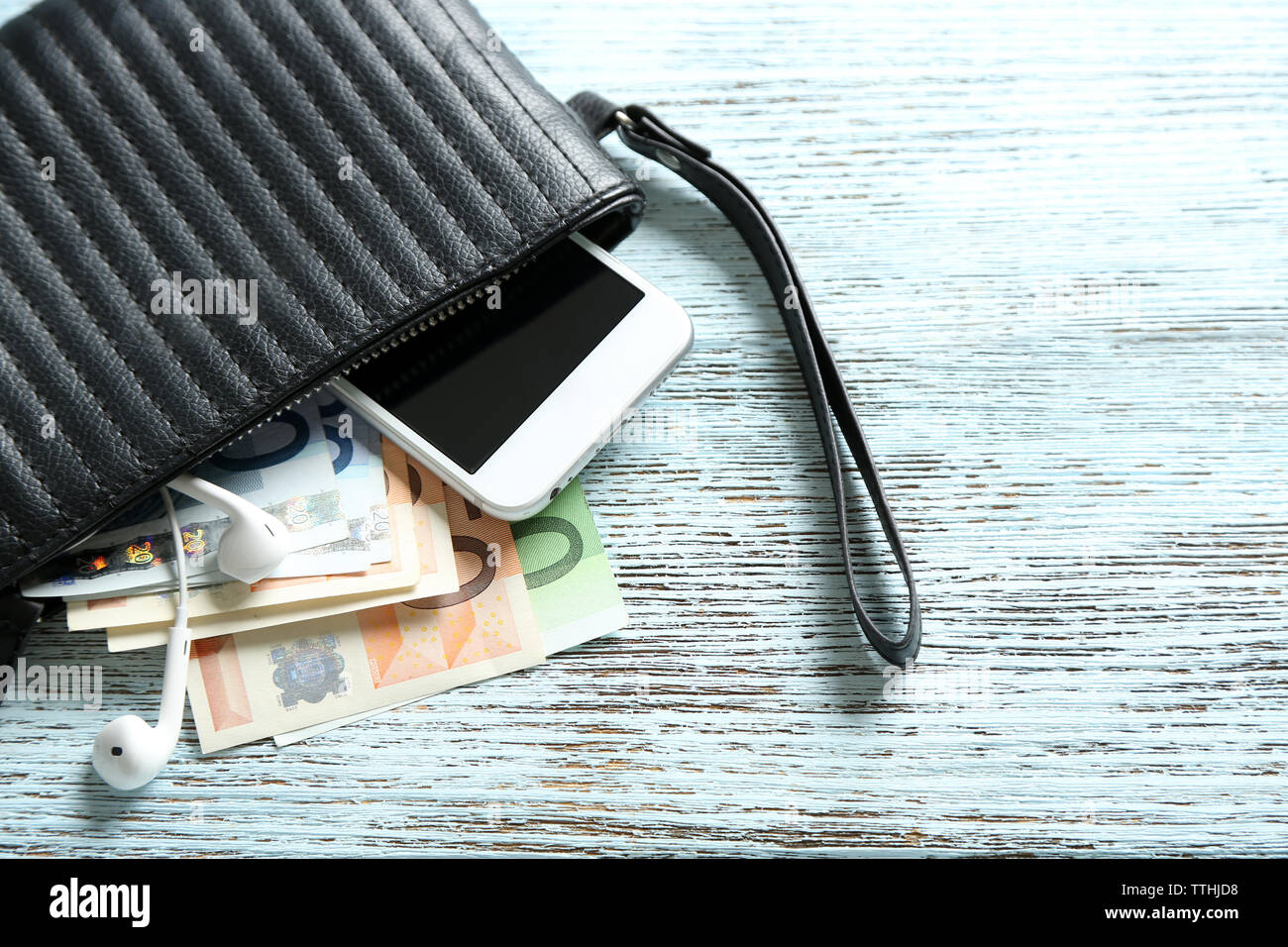 Leather purse with mobile phone and euro banknotes on wooden background Stock Photo