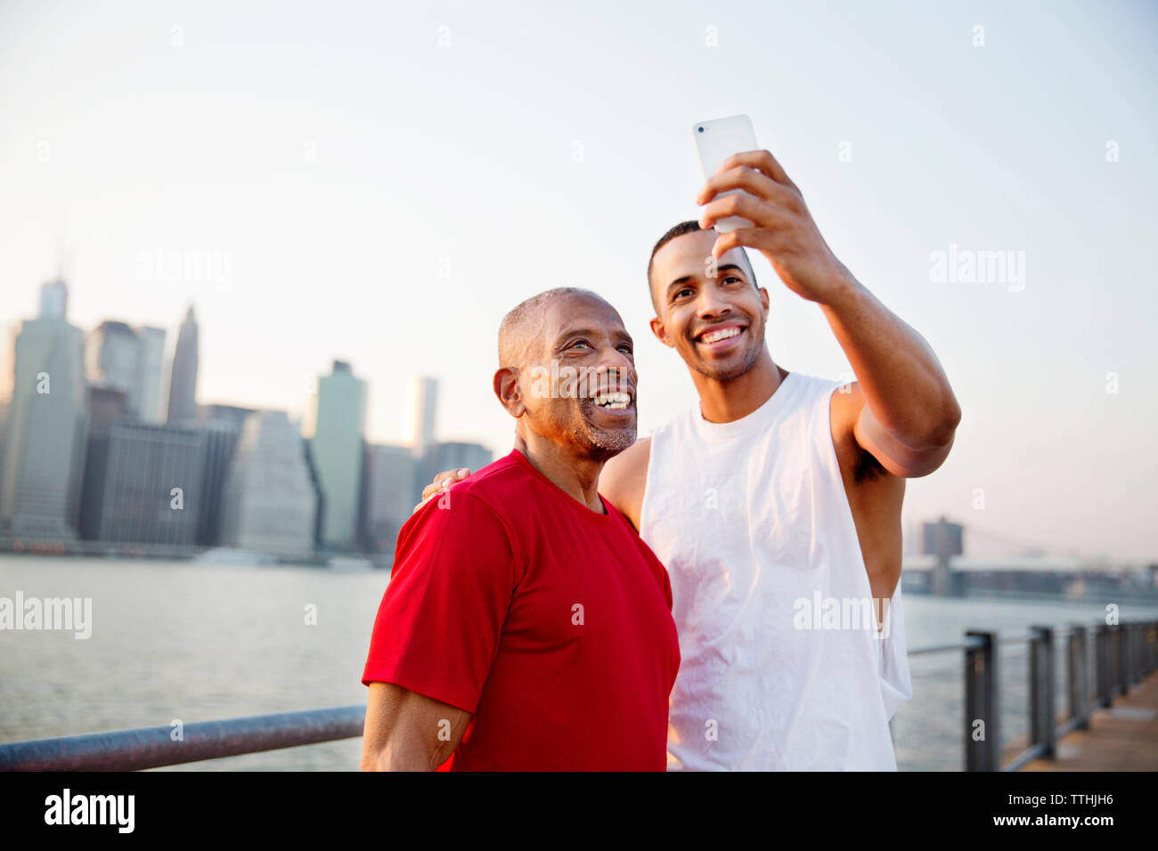 Happy man taking selfie with father by East River in city Stock Photo
