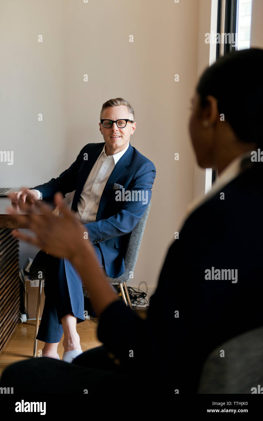 businessman discussing with female colleague while sitting in office Stock Photo