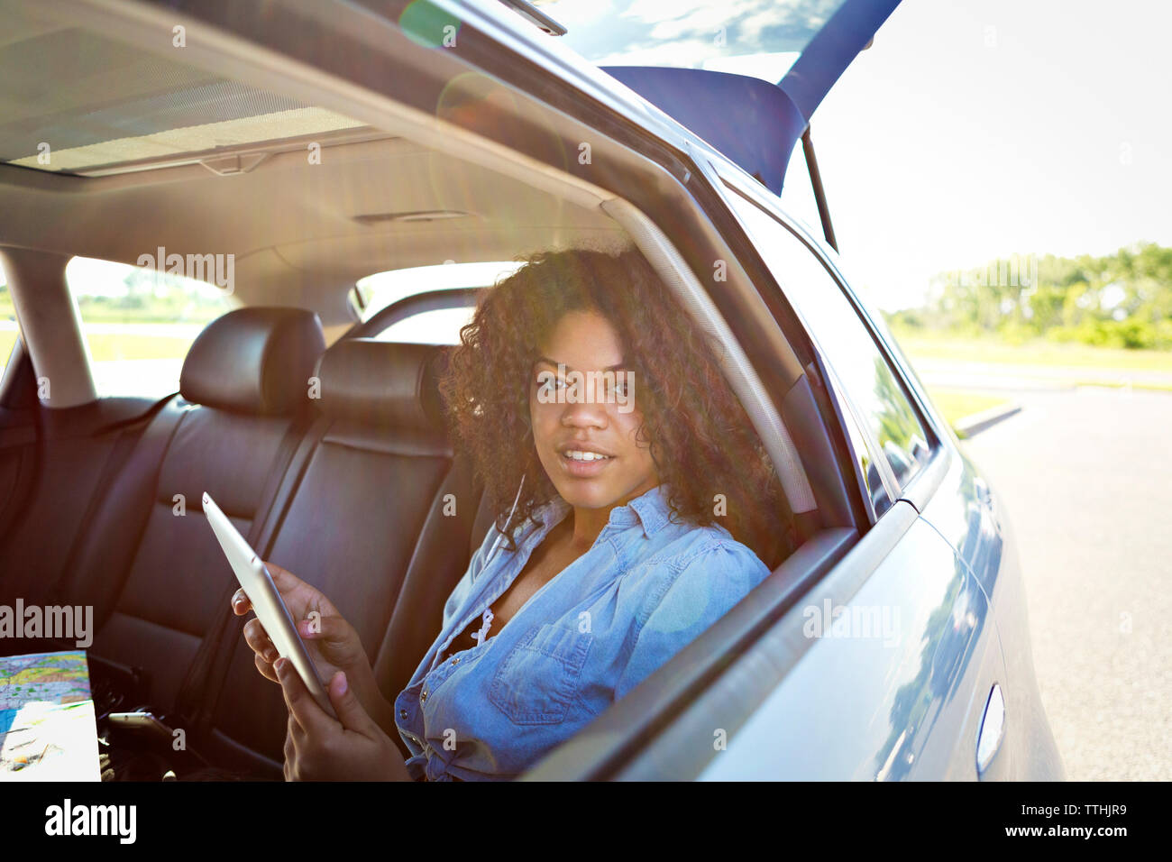 Portrait of young woman using tablet computer while traveling in car Stock Photo