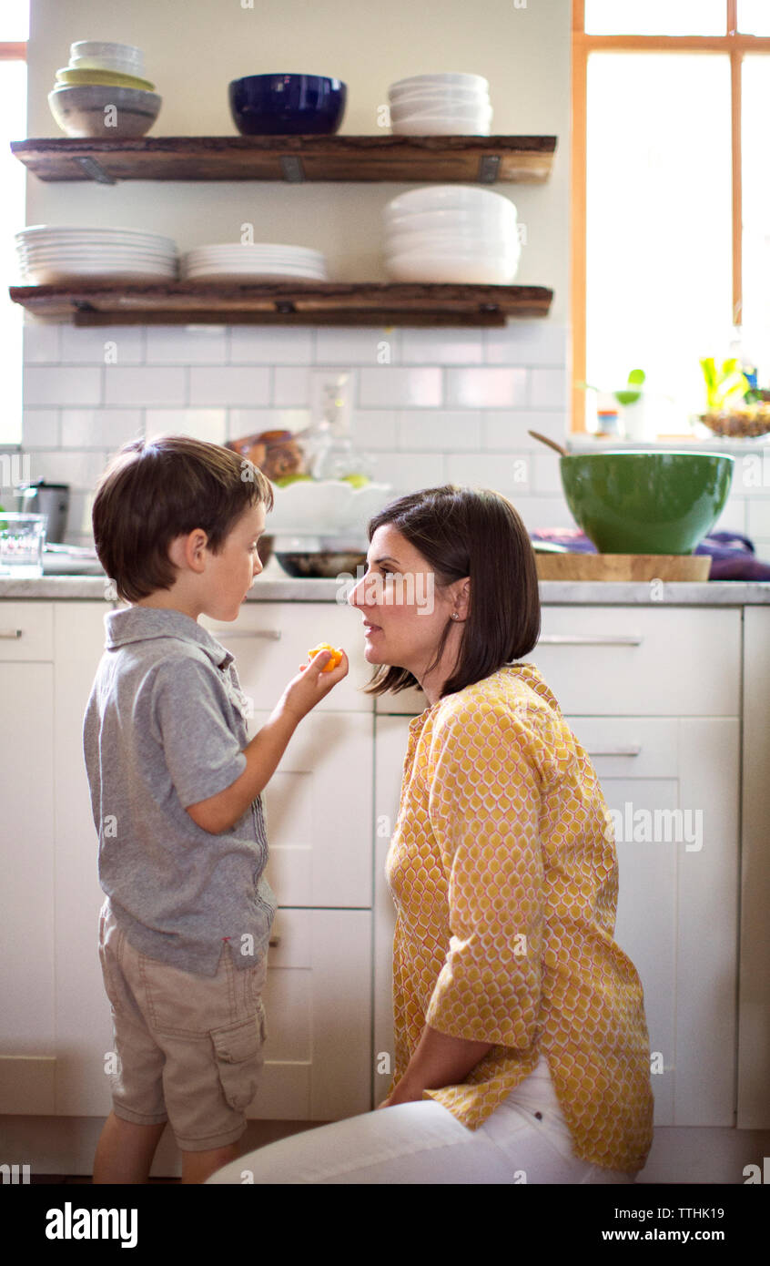 Boy talking to mother in kitchen Stock Photo