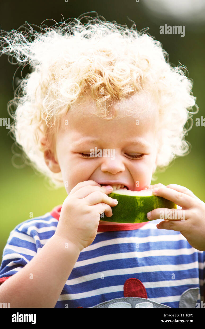 Boy with curly hair enjoying watermelon Stock Photo
