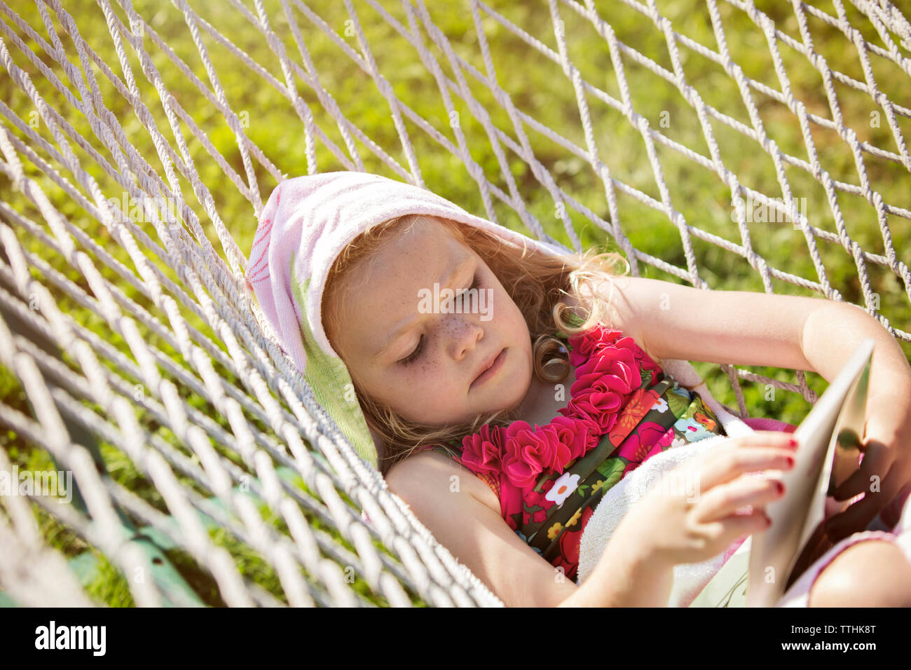 Girl reading book while lying in hammock Stock Photo - Alamy
