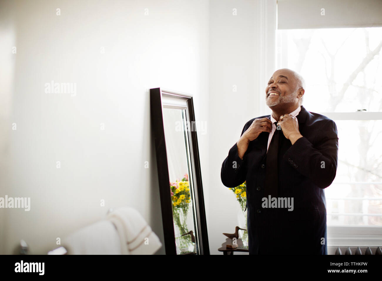 Mature man getting dressed by mirror at home Stock Photo