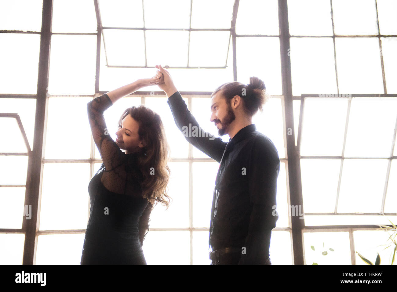 Young couple dancing against window on sunny day Stock Photo