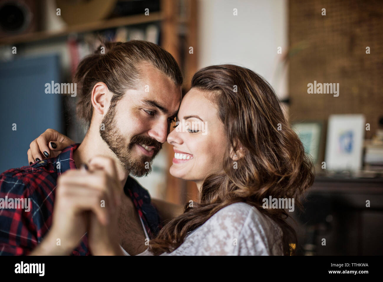 Happy young couple smiling and holding hands at home Stock Photo - Alamy