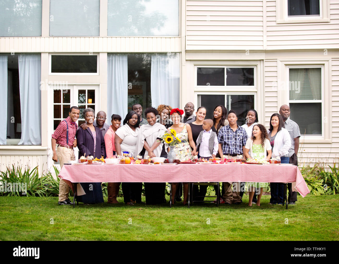 Portrait of happy family and friends standing at table against house Stock Photo