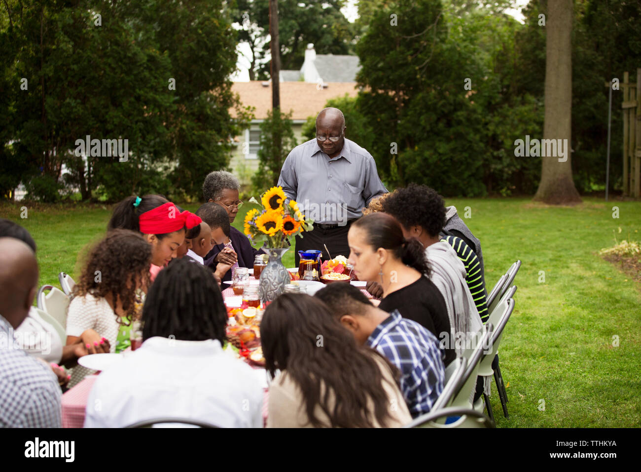 Family and friends having food at table in backyard Stock Photo