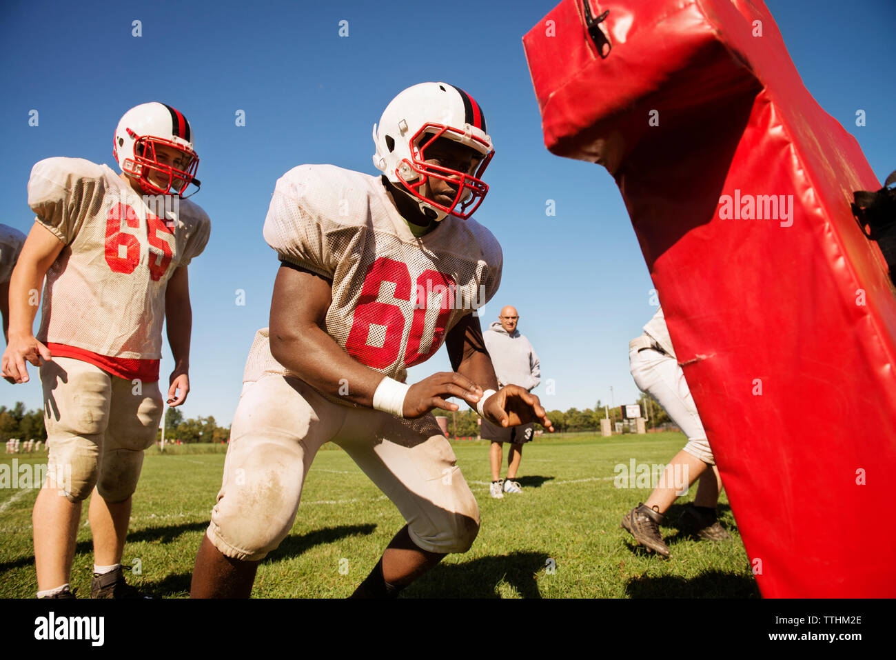 Male football players practicing on field against sky Stock Photo