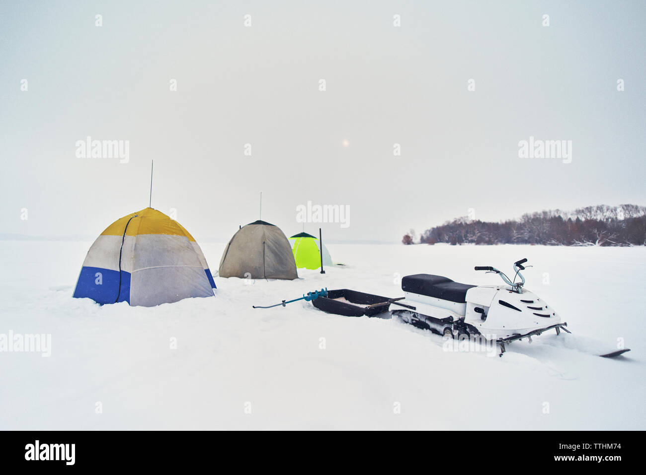 Snowmobile and tents on field against clear sky during winter Stock Photo