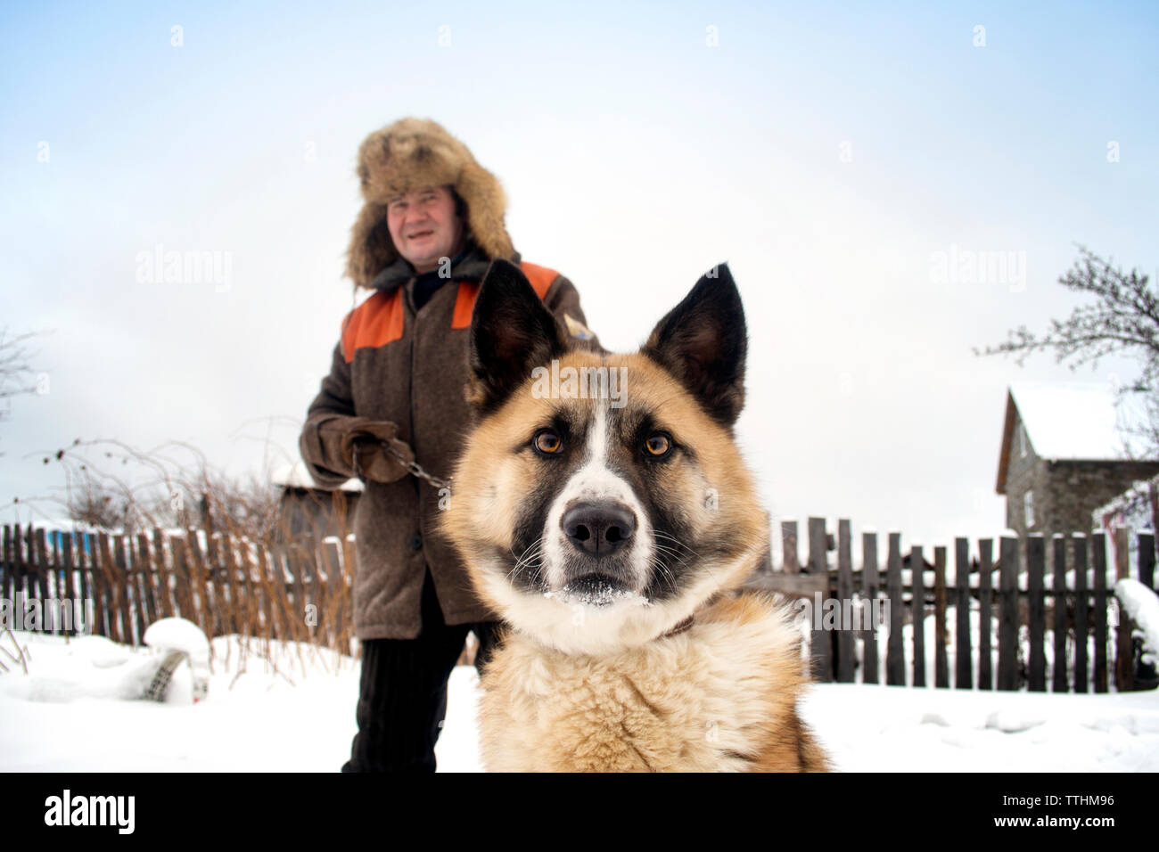 Portrait of man and dog on snow covered field Stock Photo