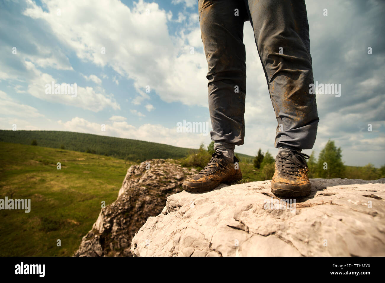Low section of person standing on rock against sky Stock Photo
