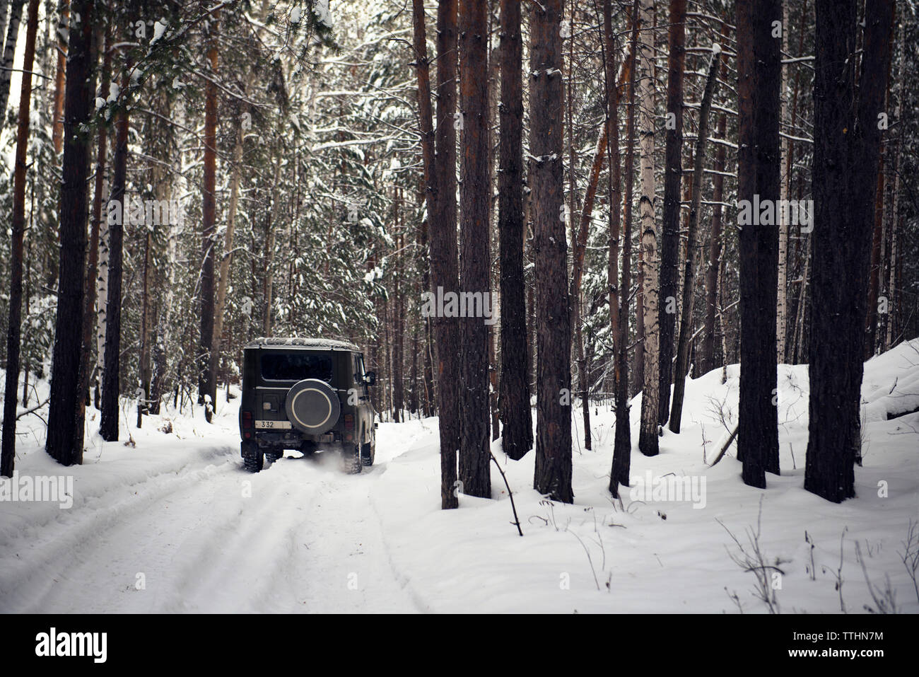 Off-road vehicle in snow covered forest Stock Photo