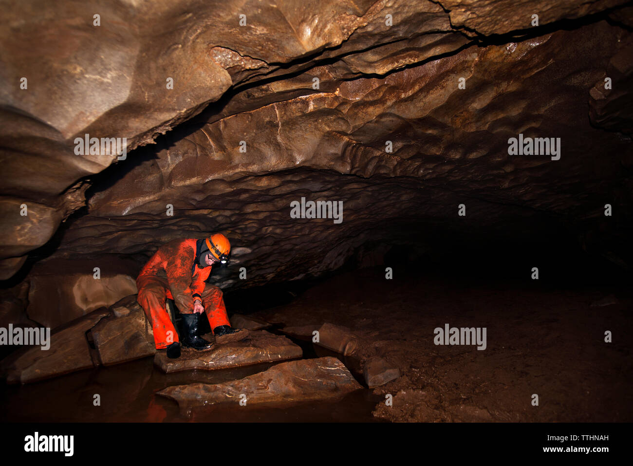 Manual worker cleaning boot while sitting in cave Stock Photo