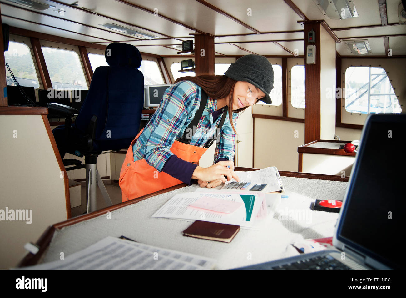 Woman using calculator and writing on documents in fishing boat Stock Photo
