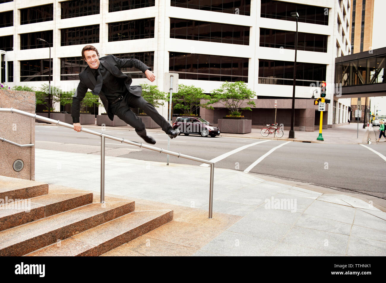 Businessman jumping over railing at sidewalk in city Stock Photo Alamy