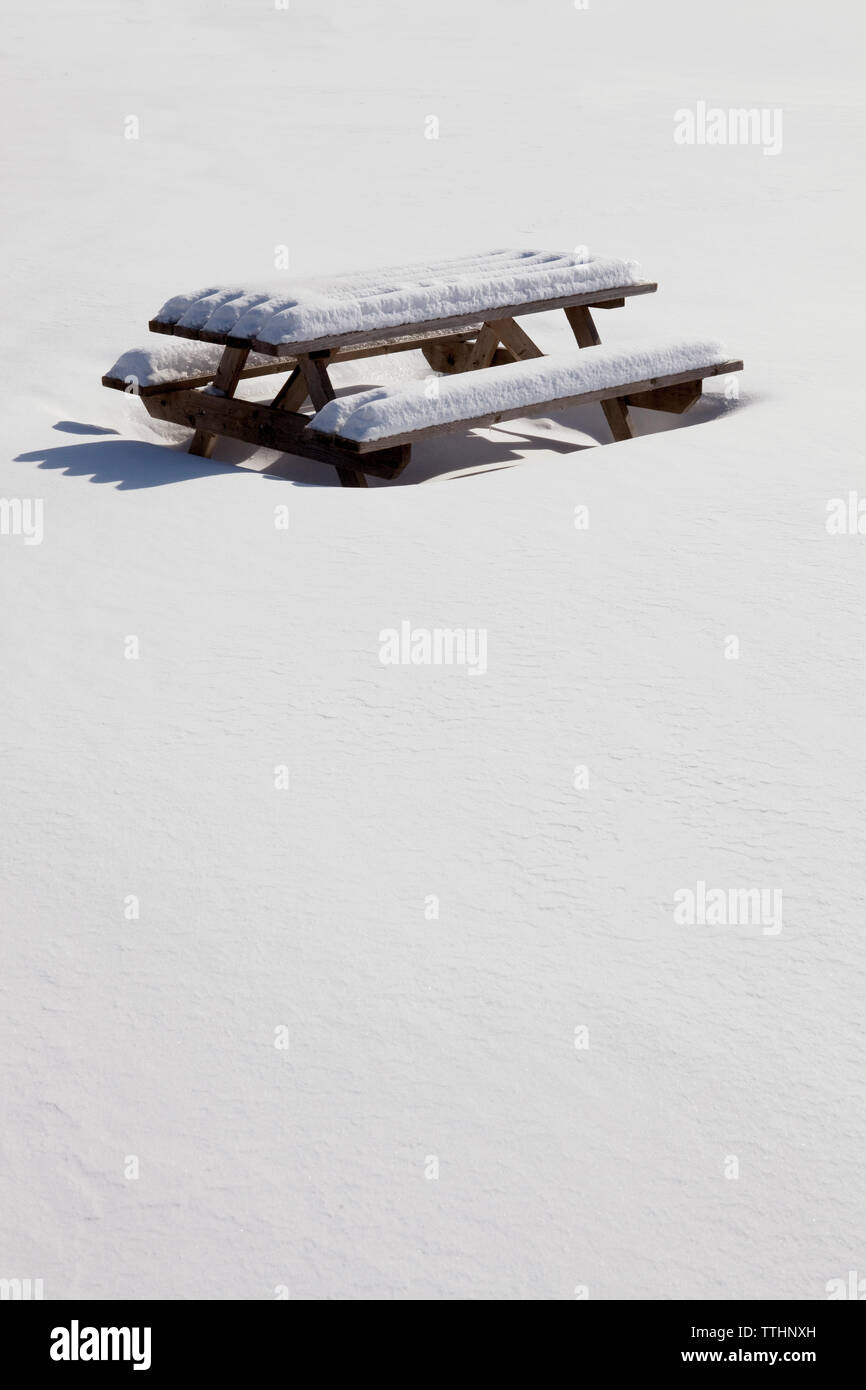 Picnic table covered with snow on field Stock Photo