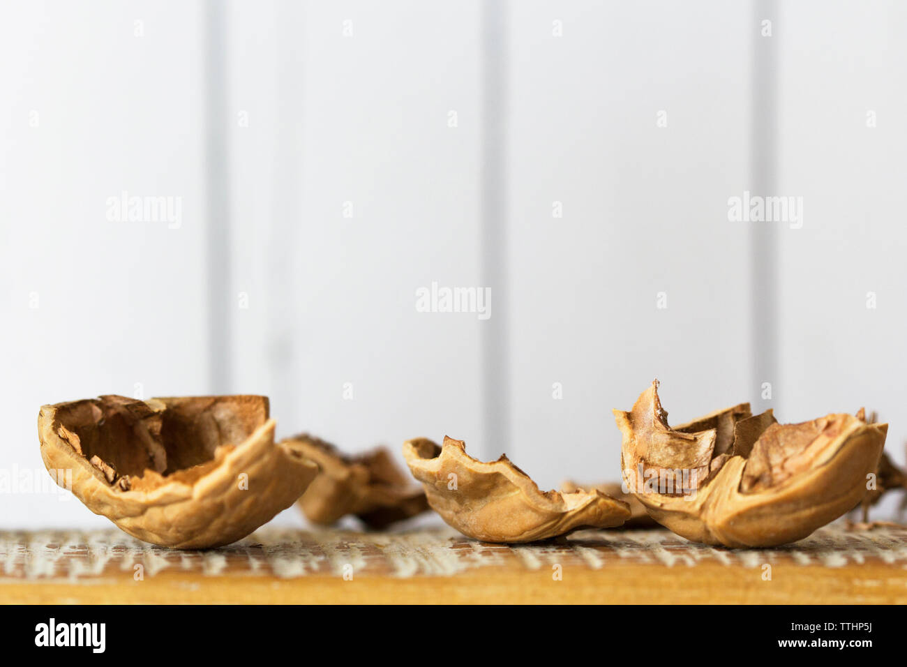 Walnut shells on cutting board against wall Stock Photo