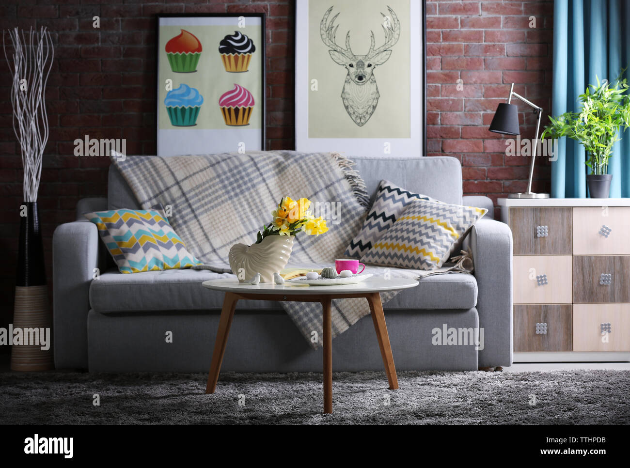Design interior of living room with grey sofa and bouquet of flowers on