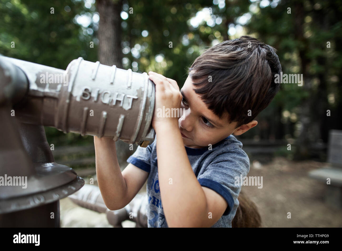 Boy looking through telescope in forest Stock Photo - Alamy