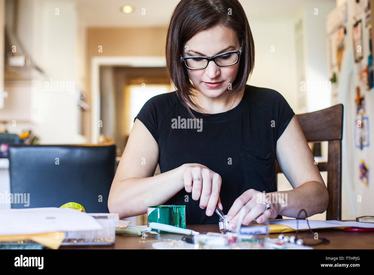 Female Artist Making Jewelry At Table In Workshop Stock Photo