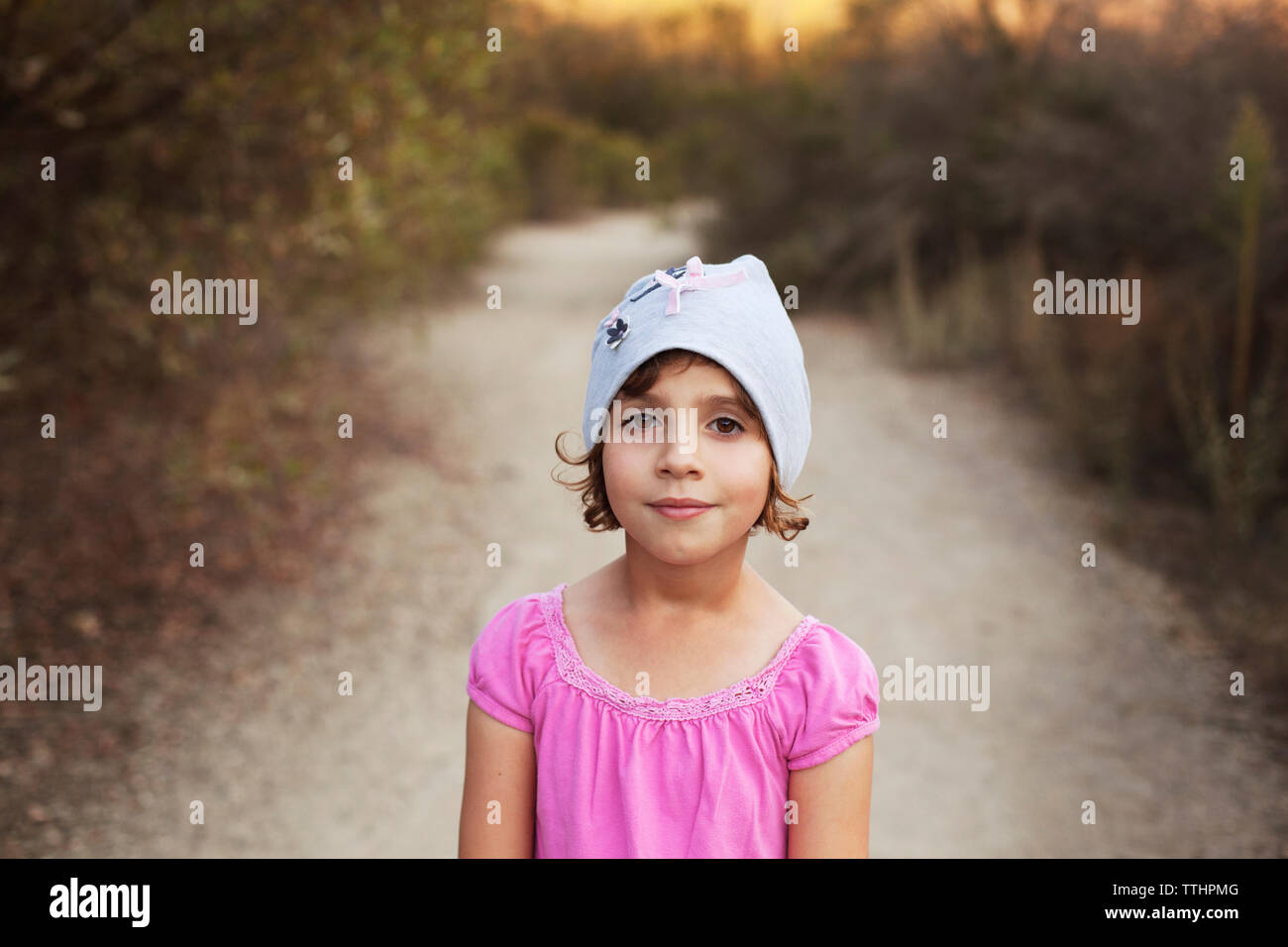 Portrait of girl wearing knit hat while standing on dirt road Stock Photo