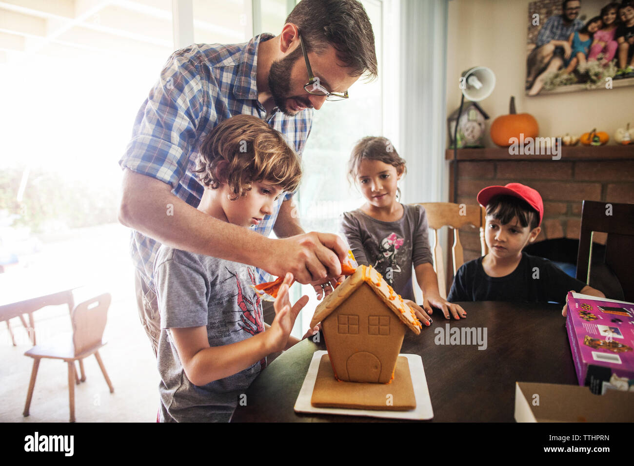 Family decorating gingerbread house at home Stock Photo