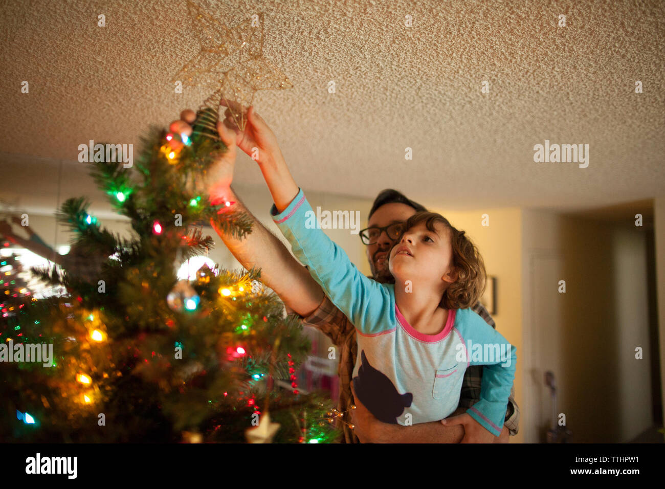 Father and daughter decorating christmas tree at home Stock Photo - Alamy