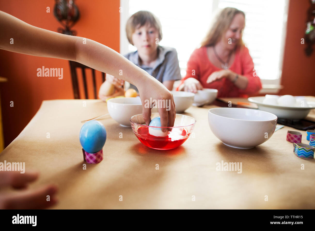 Cropped image of girl decorating Easter eggs with family at home Stock Photo
