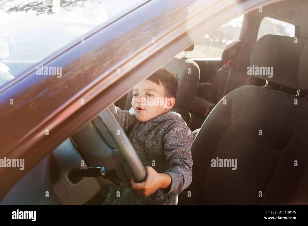 Boy pretending to drive while sitting in car Stock Photo