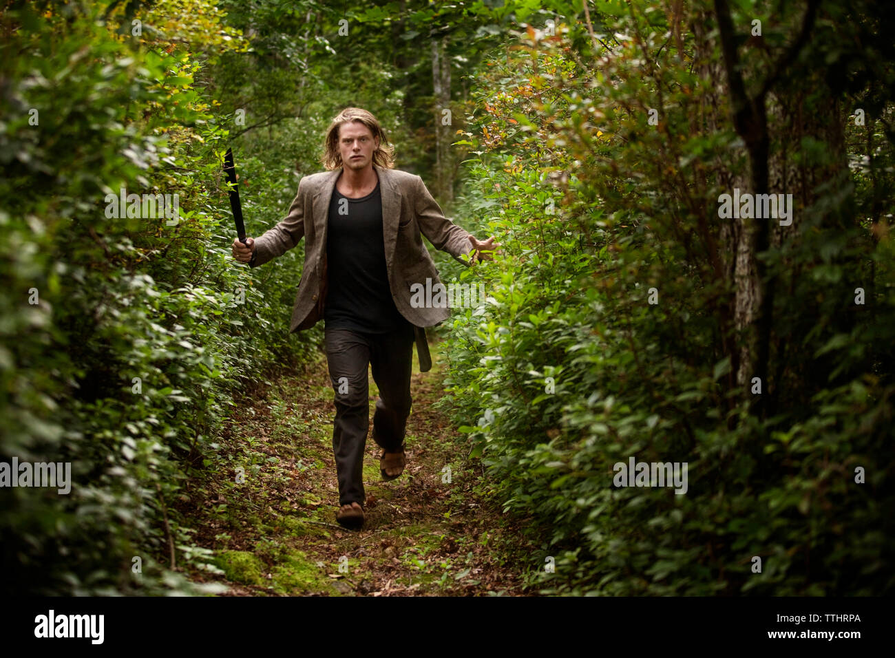 Angry man running in forest with knife Stock Photo - Alamy