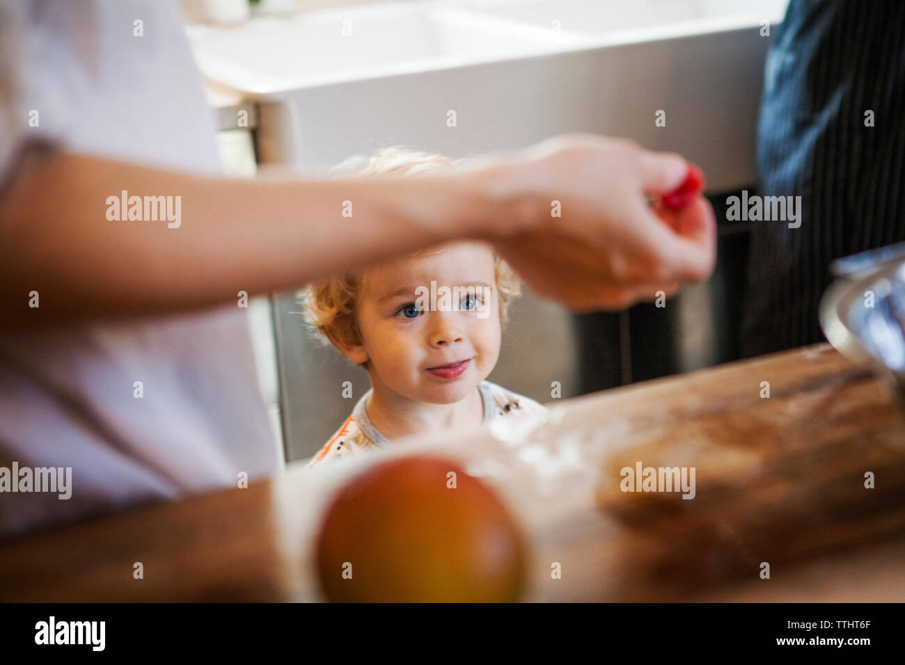 Boy looking at raspberry in kitchen Stock Photo