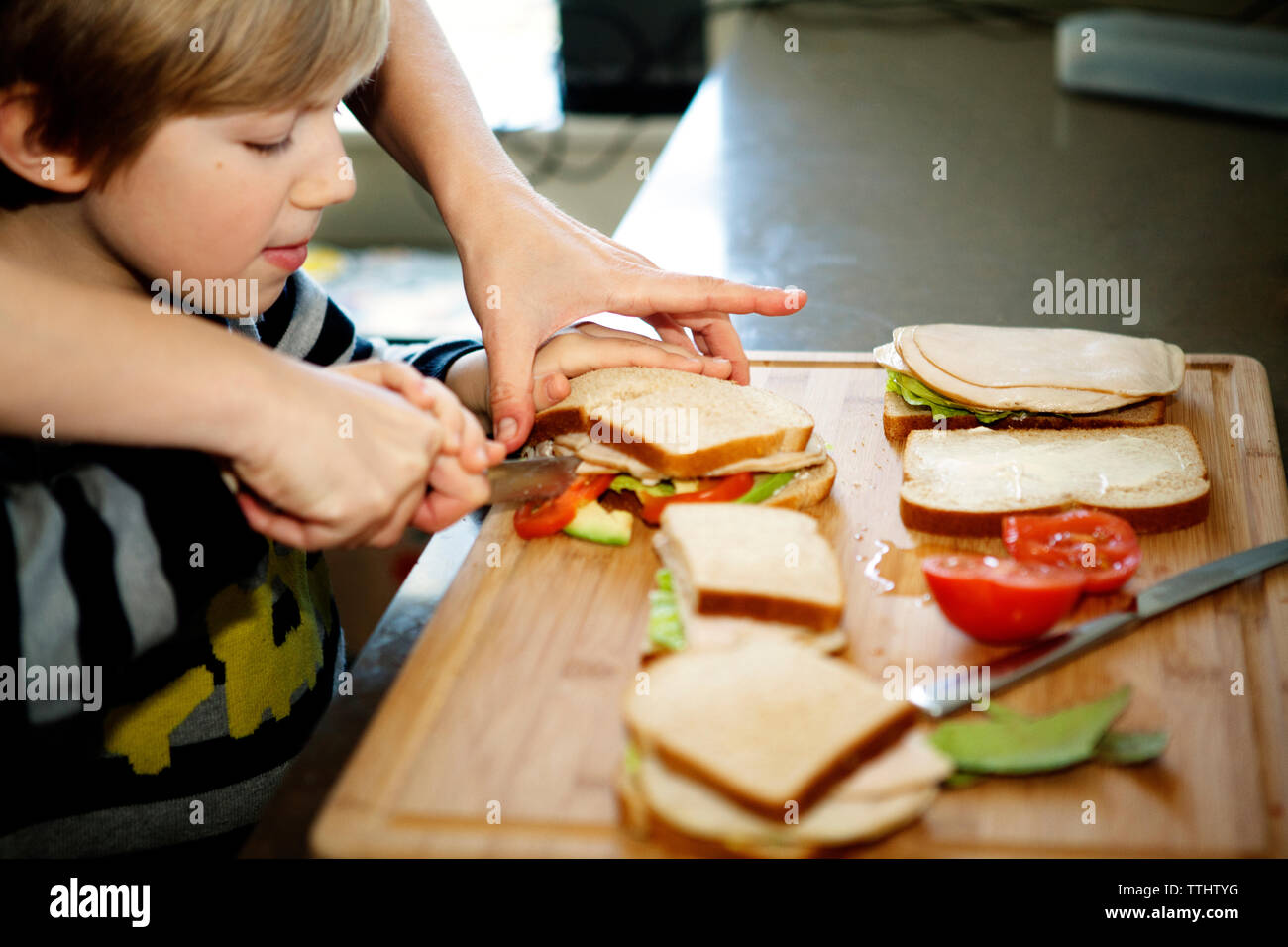 Cropped image of father making sandwich with son in kitchen Stock Photo