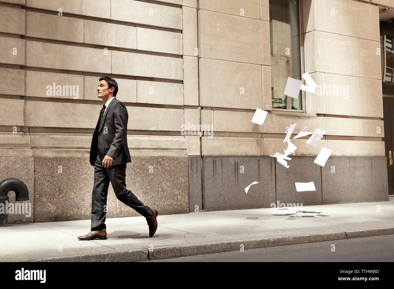 Confident businessman walking while papers flying at city street Stock ...