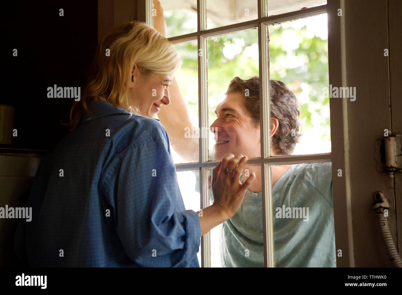 Woman looking at man through window Stock Photo
