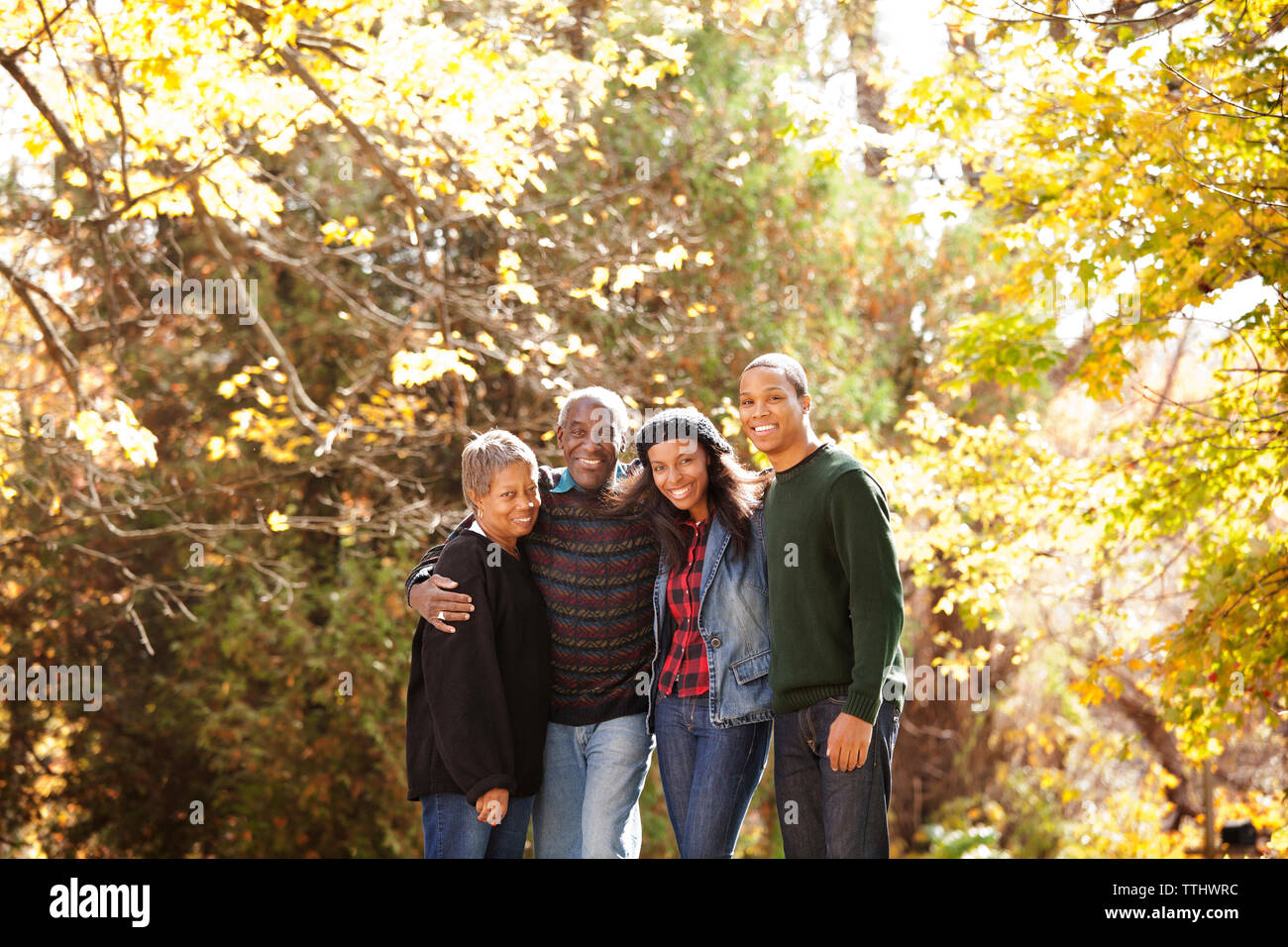 Portrait of family in forest on sunny day Stock Photo