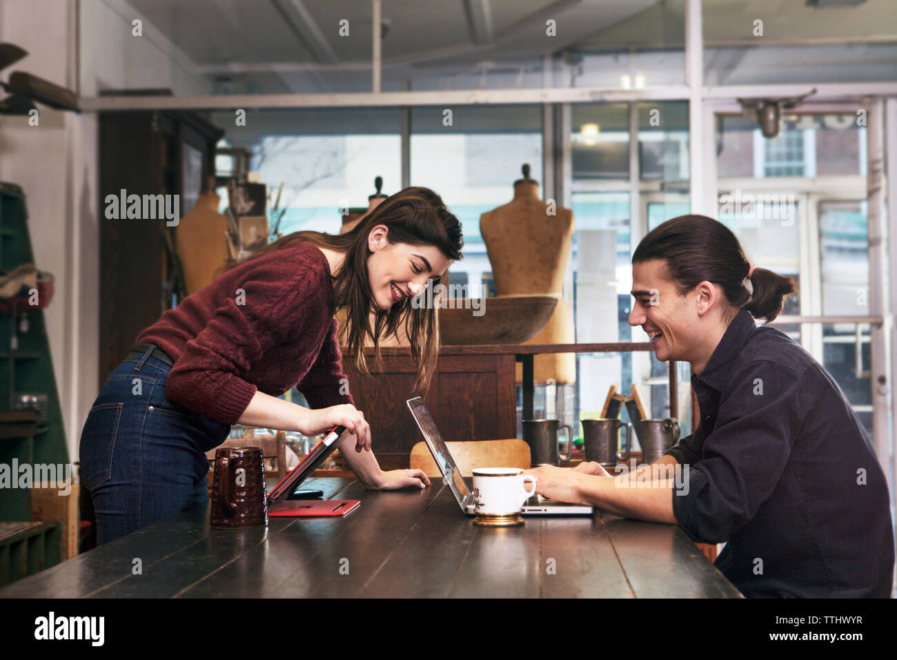 Happy couple looking at laptop computer while sitting at clothing store Stock Photo