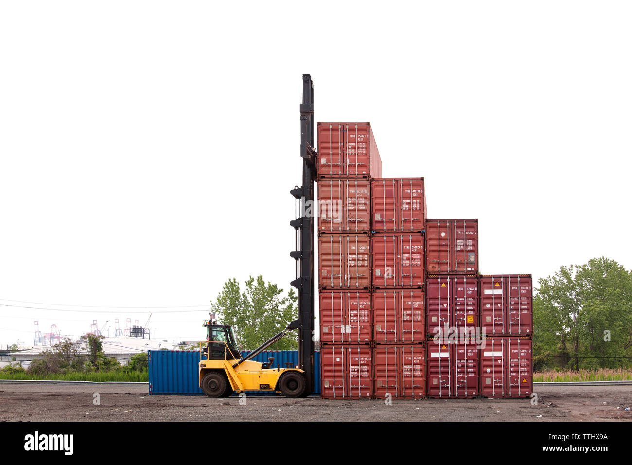 Forklift by cargo containers against clear sky Stock Photo