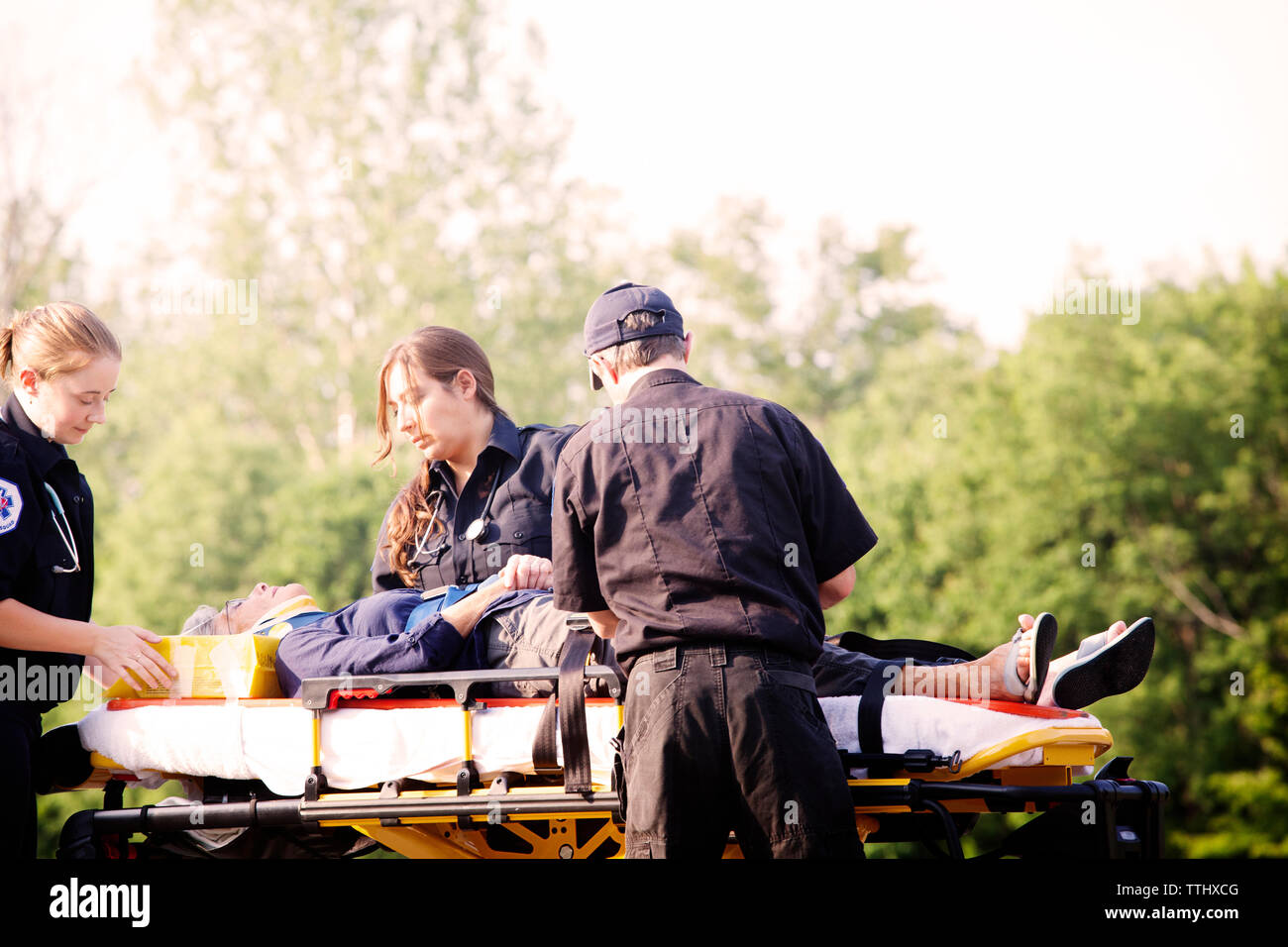 Paramedics giving treatment to patient on hospital gurney Stock Photo