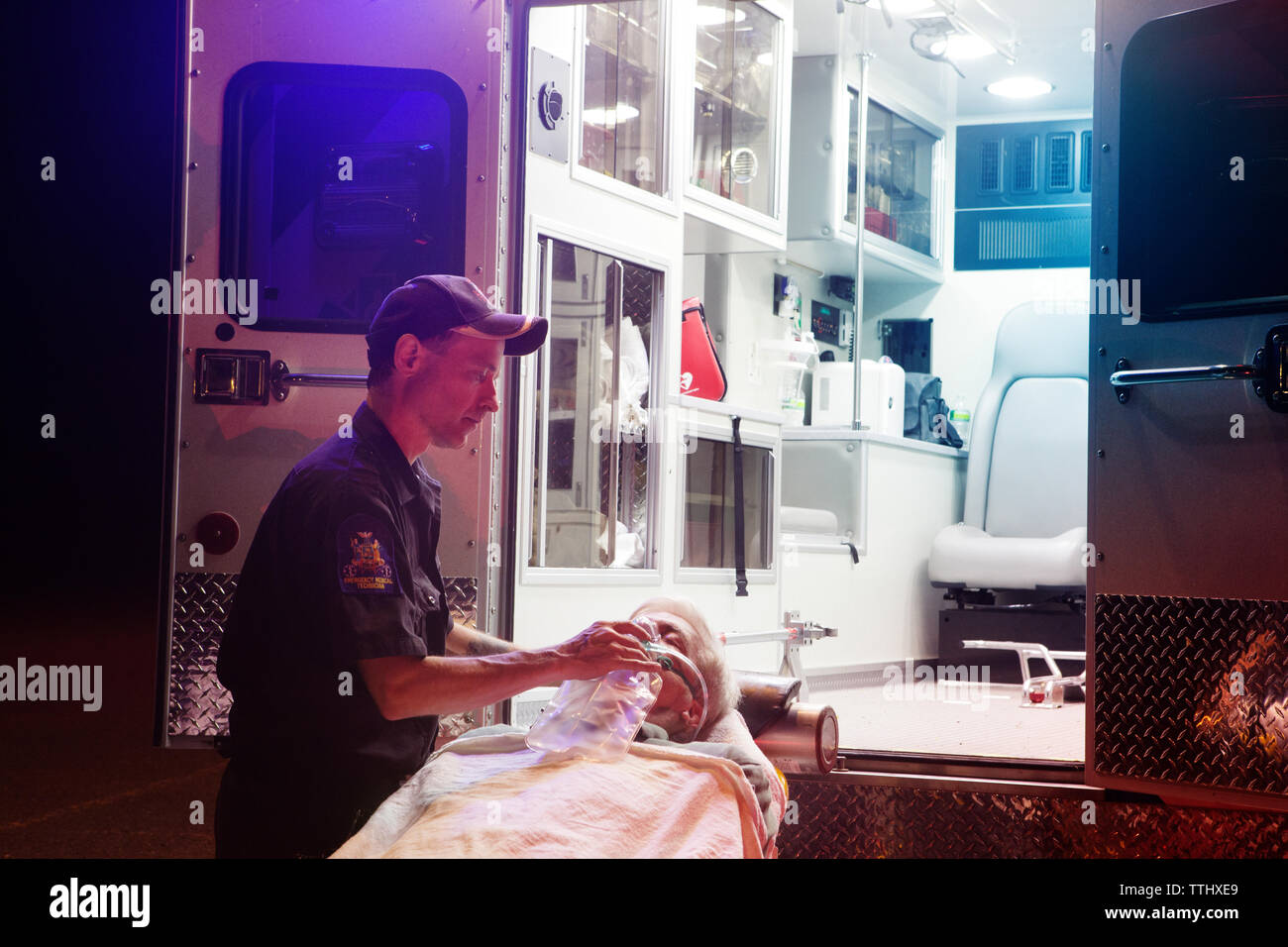 Paramedics giving treatment to patient on hospital gurney at night