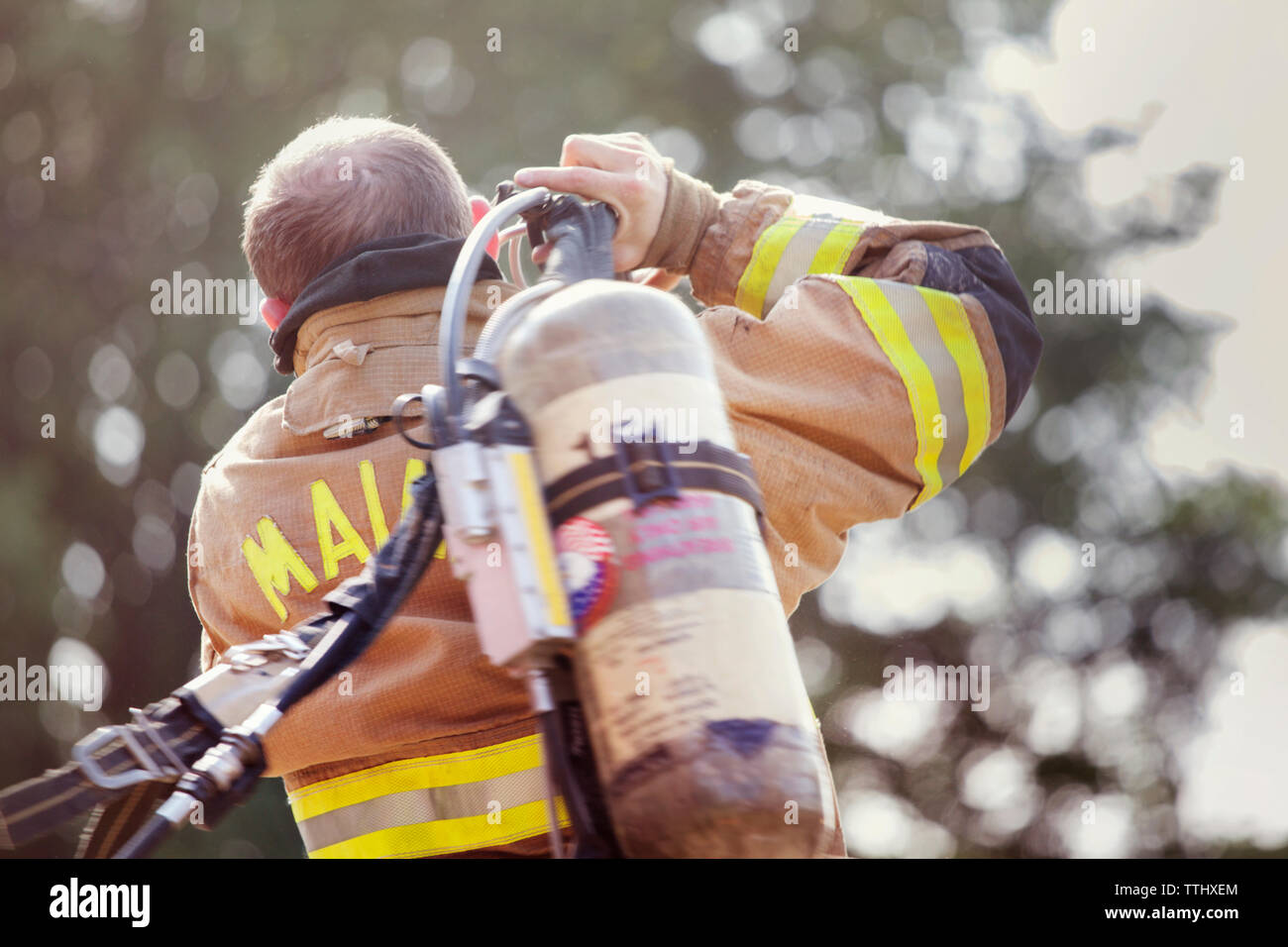 Rear view of man carrying fire extinguisher Stock Photo
