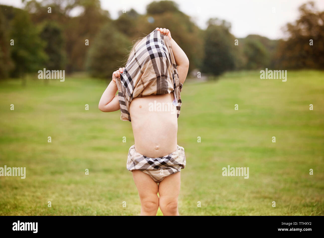 Girl covering face with dress while standing at park Stock Photo