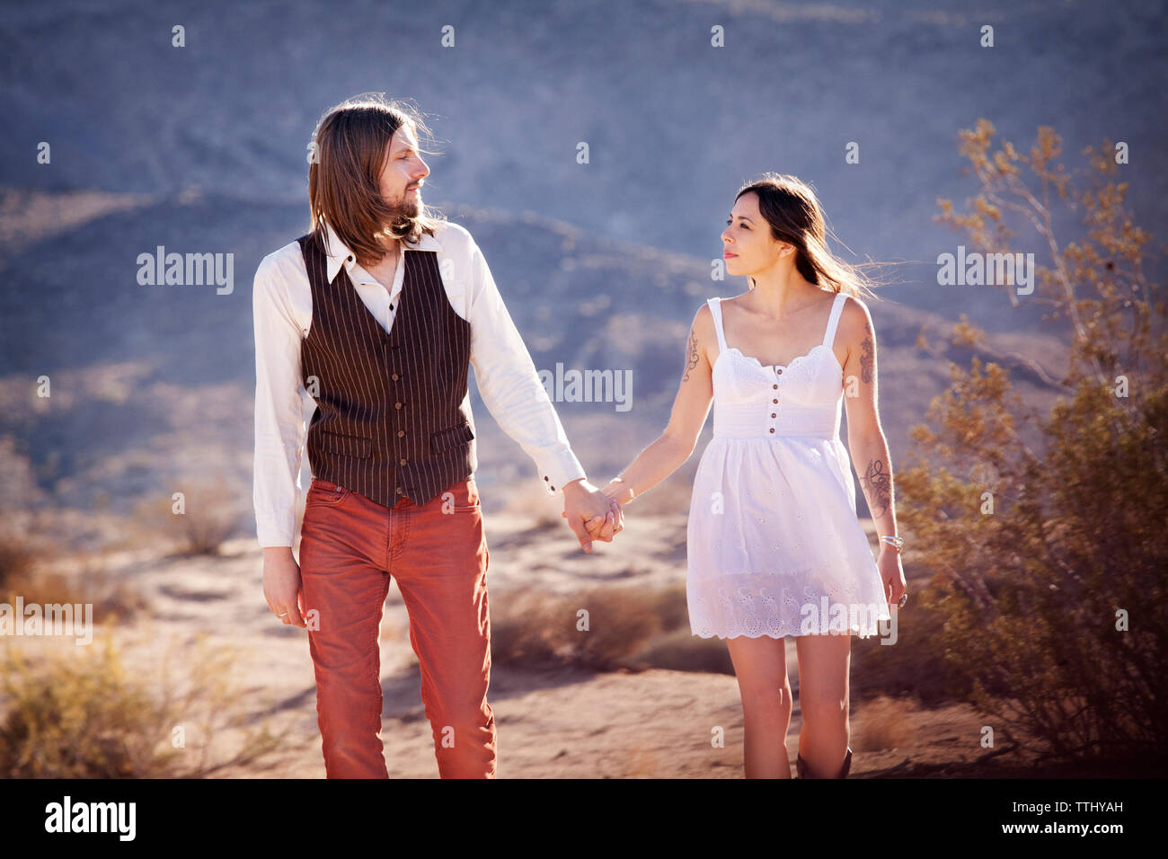 Couple holding hands while walking on field Stock Photo - Alamy